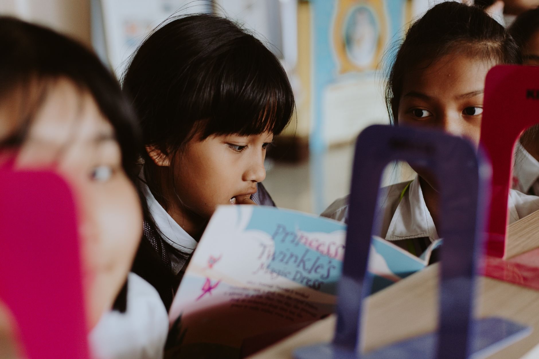 Group of children reading books together in a classroom setting.